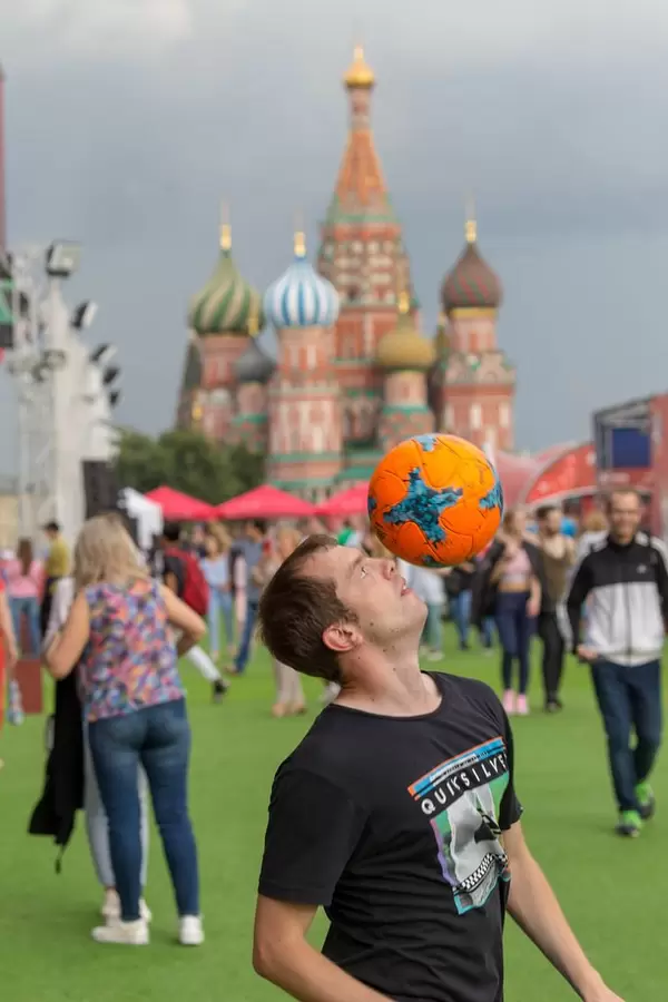 Guy balancing a soccer ball on his head. Saint Basil's Cathedral in the background