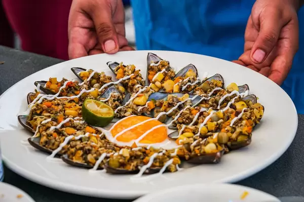 Guy serving a delicious greenshell mussel dish
