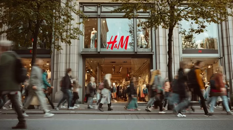 H&M Laden mit Menschenmenge und herbstlichen Bäumen