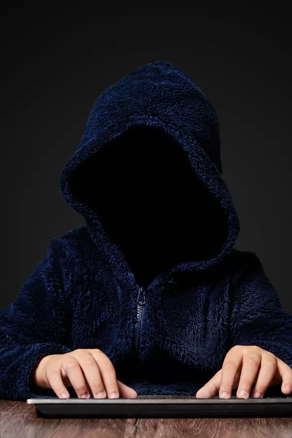 Hacker working in the dark. Faceless hooded anonymous computer hacker