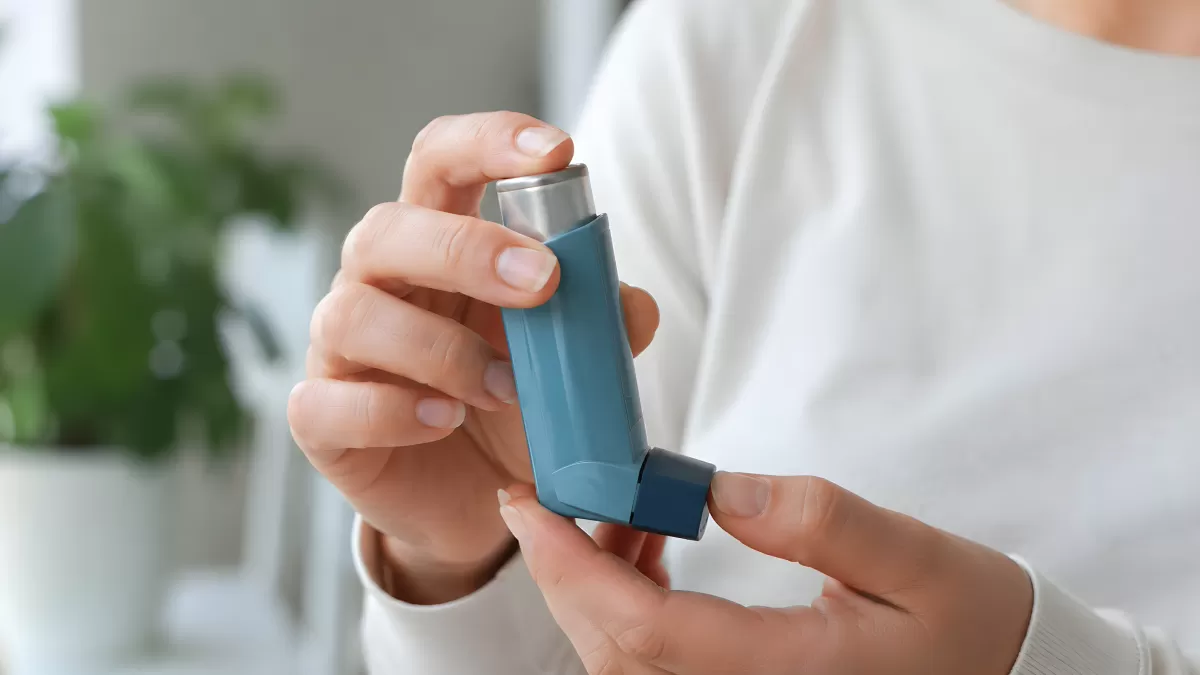 Hände halten blauen Asthma-Inhalator aus nächster Nähe