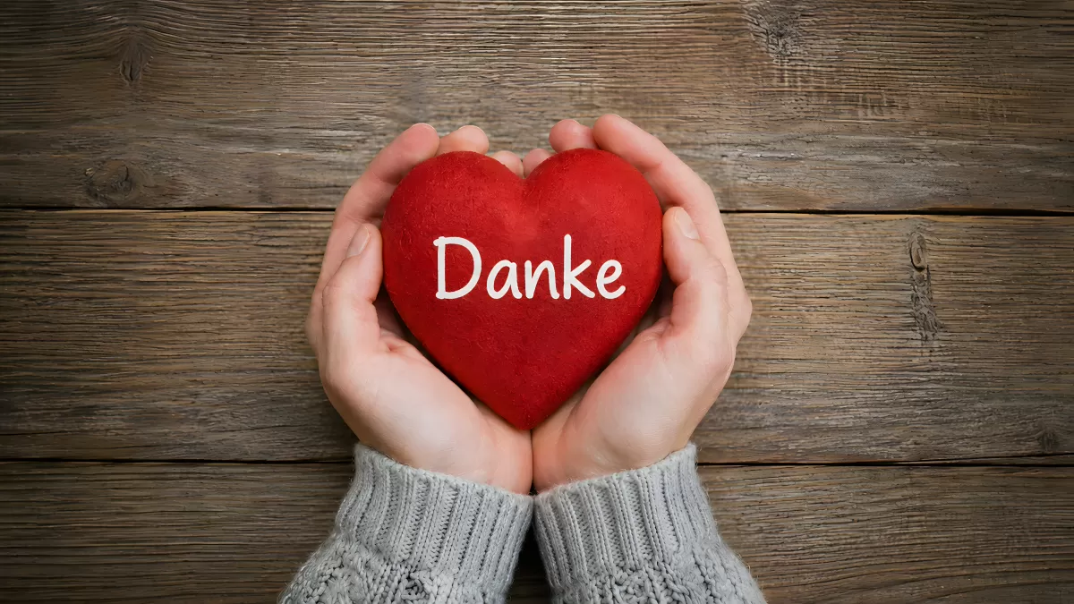 Hände halten rotes Herz mit Danke-Schriftzug