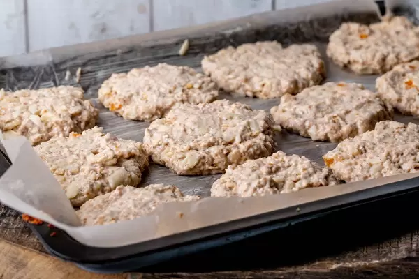 Haferflocken Cookie-Dough-Plätzchenteig mit mit Äpfeln und getrockneten Aprikose auf eingefettete Backpapier auf einem Backblech