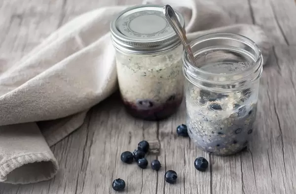 Haferflocken mit Blaubeeren in Gläser auf einem rustikalen Holztisch