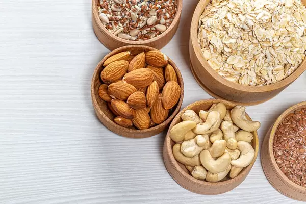 Haferflocken mit Mandeln, Cashews, Leinsamen und Sonnenblumenkernen, auf einem weißen Tisch