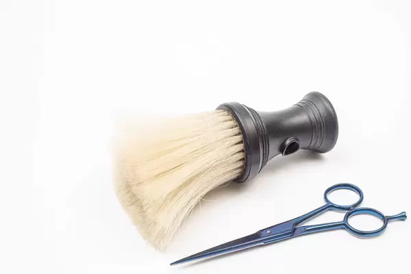 Haircut scissors with brush isolated above white background