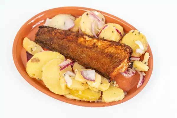 Hake fish served on the plate with Potatoes salad above white background (Flip 2019)