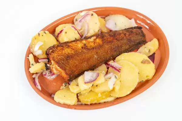 Hake fish served on the plate with Potatoes salad above white background