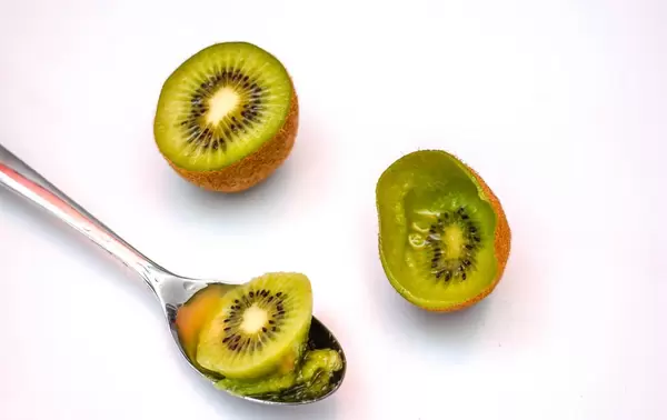 Halbierte Kiwi mit Fruchtfleisch im Löffel