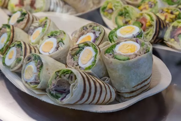 Halbierte Wraps gefüllt mit Thunfisch, hartgekochtem Ei, Oliven und Salat auf Platte