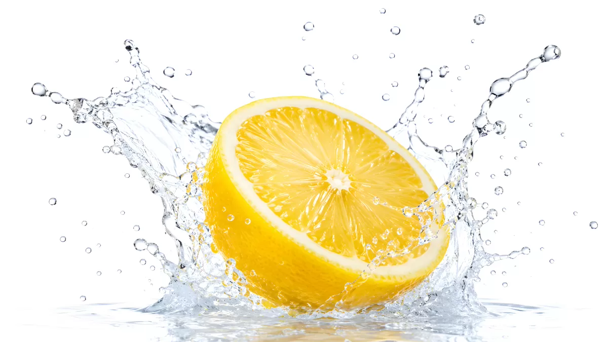Halbierte Zitrone mit Wasserspritzer vor weißem Hintergrund