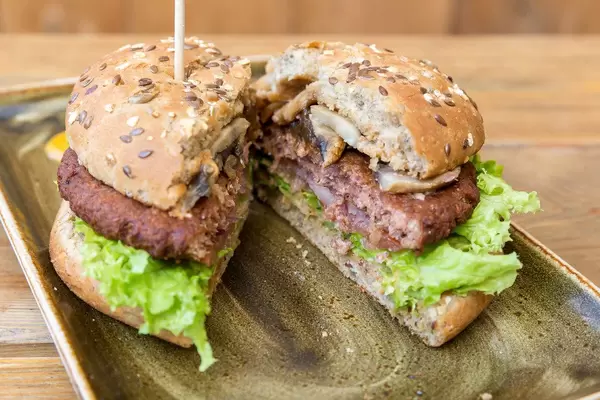 Halbierter Vitamin B12 - Burger "Naturbursche" von Moving Mountains bei "Hans im Glück", mit Pilzen, Pflanzenbratling und karamellisierten Zwiebelringen