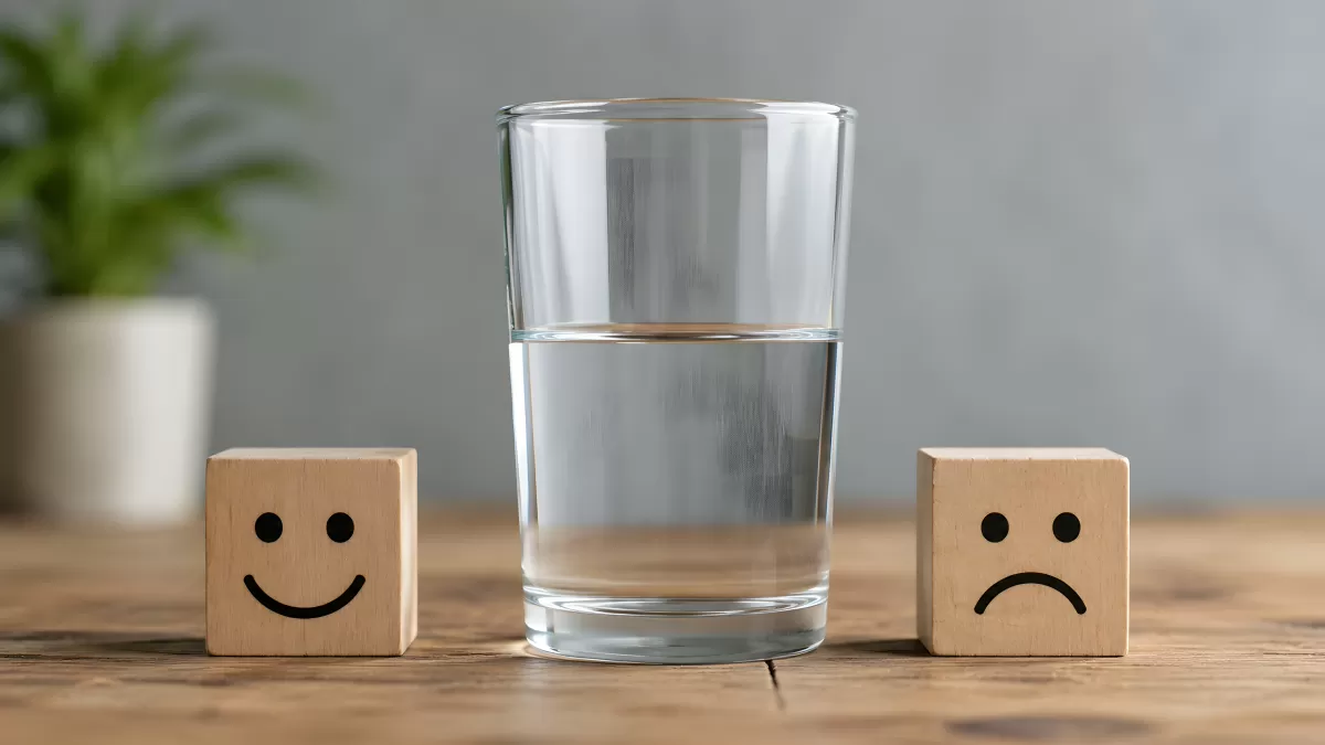 Halbvolles Wasserglas zwischen Holzwürfeln mit Emoticons