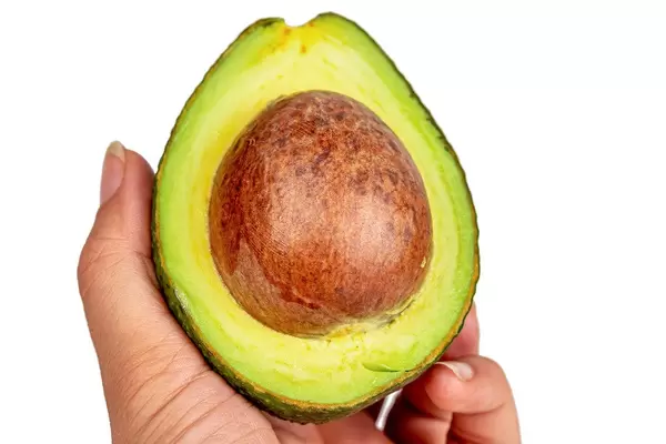 Half a fresh avocado in a woman's hand