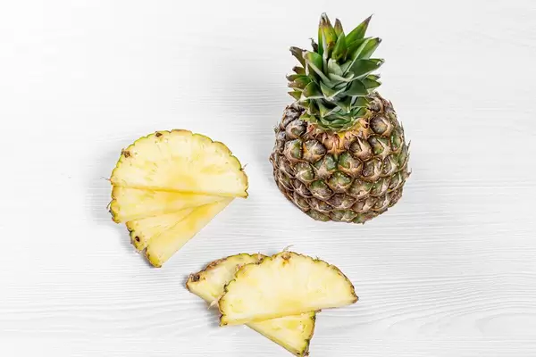 Half and pieces of fresh pineapple on white background