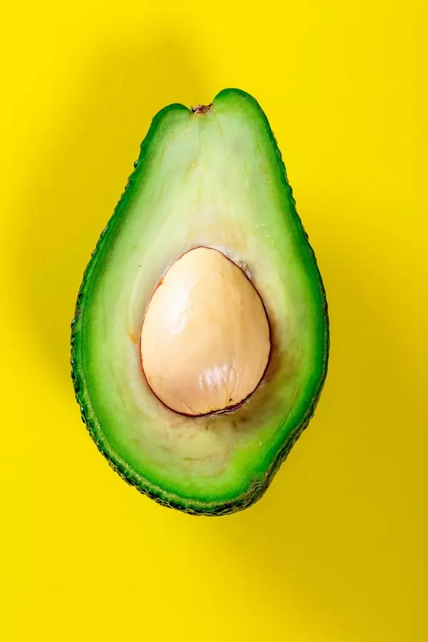 Half Avocado with the pit on a yellow background