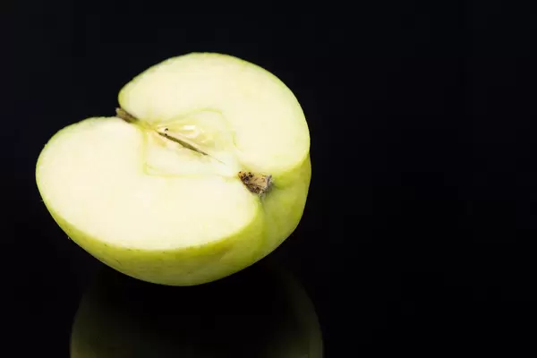 Half of a Green Apple above black reflective background (Flip 2019)