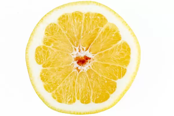 Half of a ripe yellow grapefruit on a white background