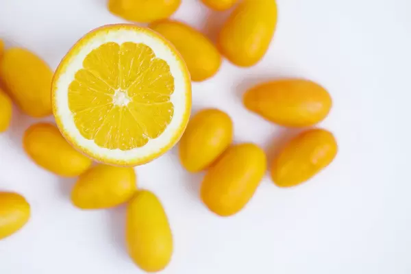 Half orange fruit and kumquats on white background (Flip 2019)
