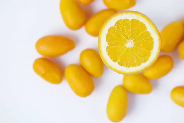 Half orange fruit and kumquats on white background
