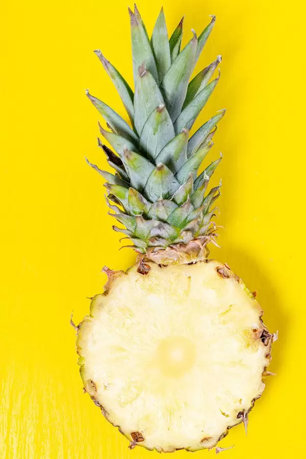 Half ripe pineapple with green leaves on a yellow background (Flip 2019)