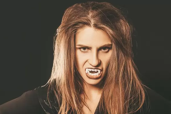 Halloween portrait of vampire woman with sharp fangs