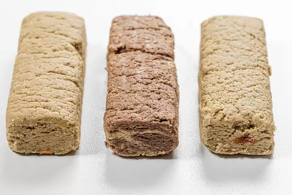 Halva dessert with peanuts, raisins and cacao on white (Flip 2019)