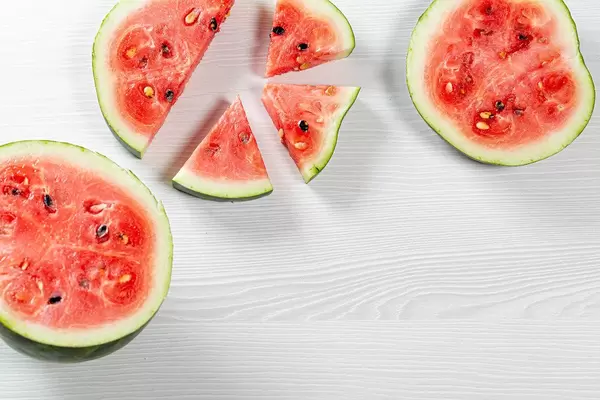 Halves and pieces of watermelon on white wooden background. Top view