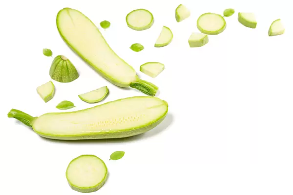 Halves and sliced zucchini on white background