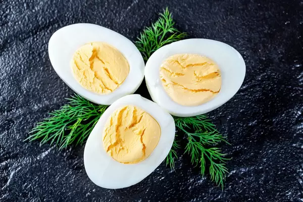 Halves of cut boiled chicken eggs on dark background
