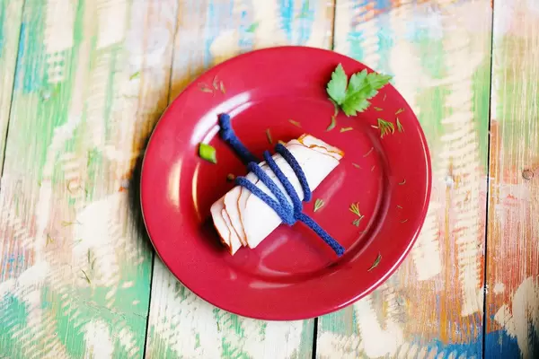 Ham in red plate, wooden background