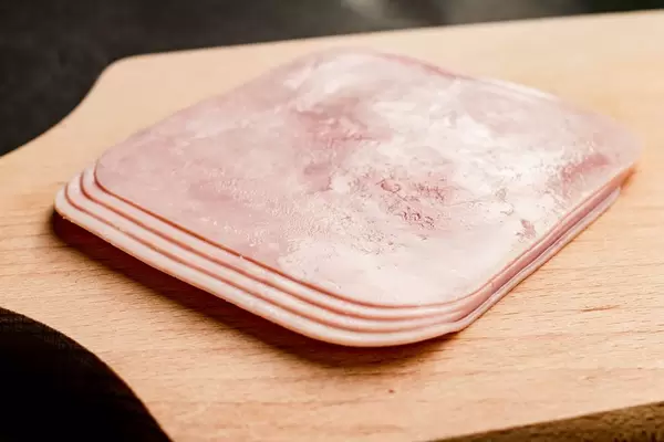 Ham slices on wooden board.