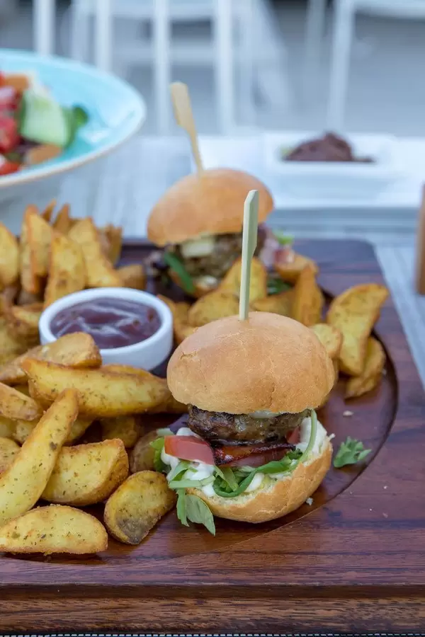 Hamburgers and roast potatoes on a wooden cutting board
