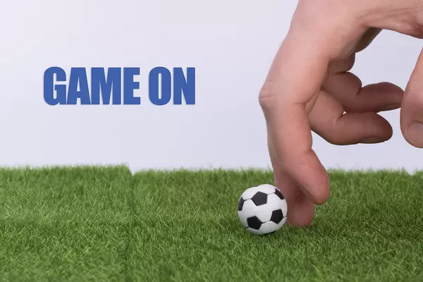 Hand and soccer ball with Game on text