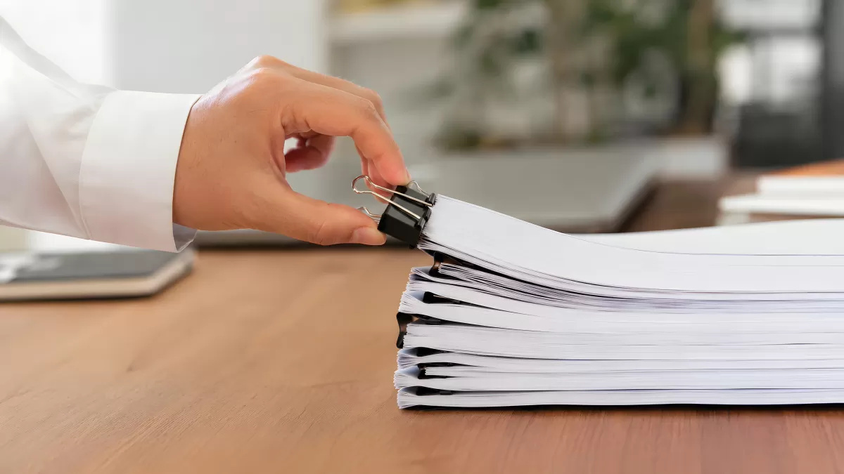 Hand befestigt Binderclip an großem Papierstapel