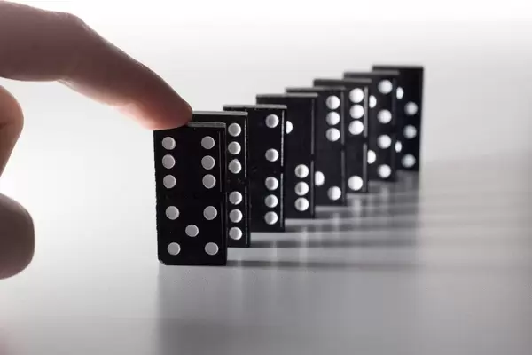 Hand bringt Dominosteine zum Sturz