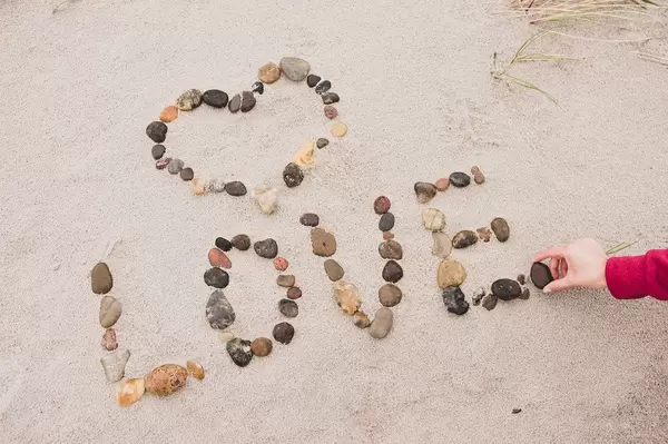 Hand completing the word LOVE with stones