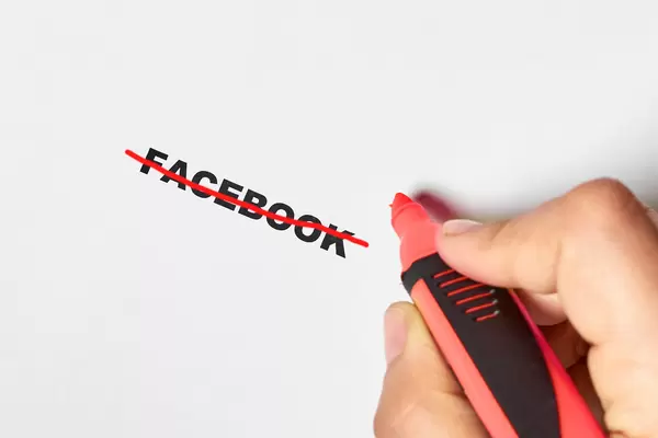 Hand crossing with line over Facebook - symbol of weak security of Facebook