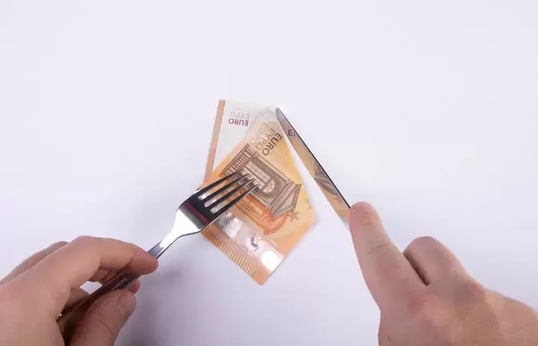 Hand cutting 50 euro banknote with fork and knife