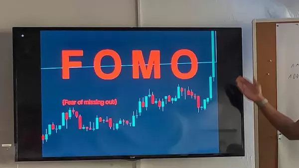 Hand deutet auf einen Fernsehbildschirm mit der Aufschrift "FOMO" - Fear of missing out, übersetzt: Die Angst, etwas zu verpassen