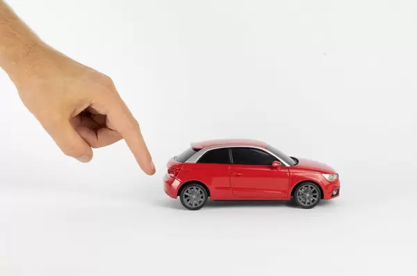 Hand gibt dem Spielzeugauto einen Schubs