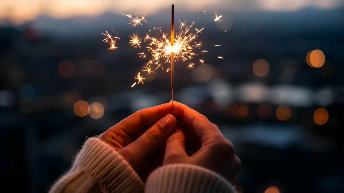Hand hält brennende Wunderkerze in der Abenddämmerung