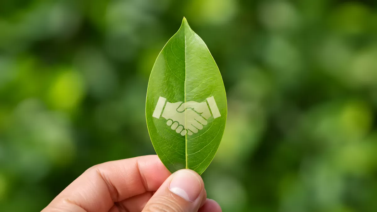 Hand hält grünes Blatt mit Händeschütteln-Symbol