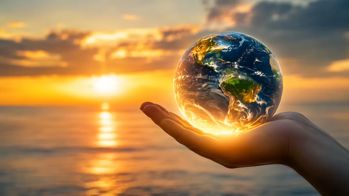 Hand hält leuchtende Erdkugel beim Sonnenuntergang