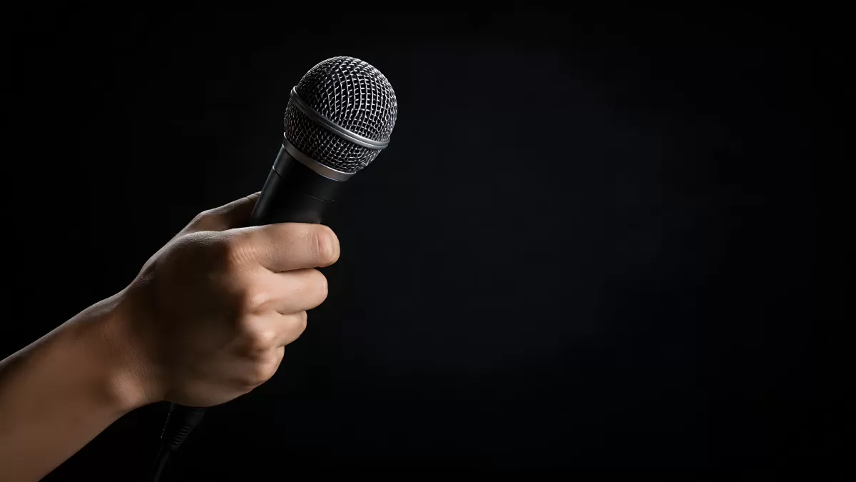 Hand hält Mikrofon vor dunklem Hintergrund