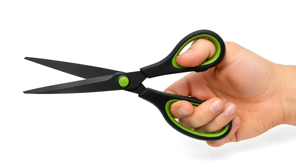 Hand hält schwarze Schere mit grünen Handgriffen