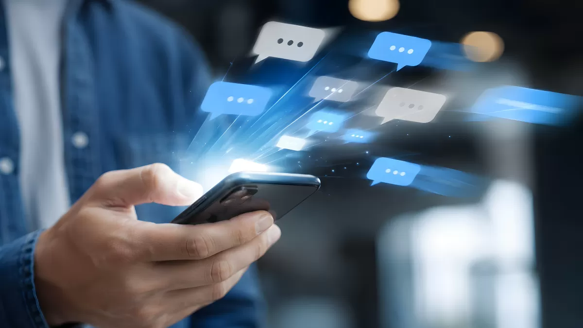 Hand hält Smartphone mit fliegenden Sprechblasen