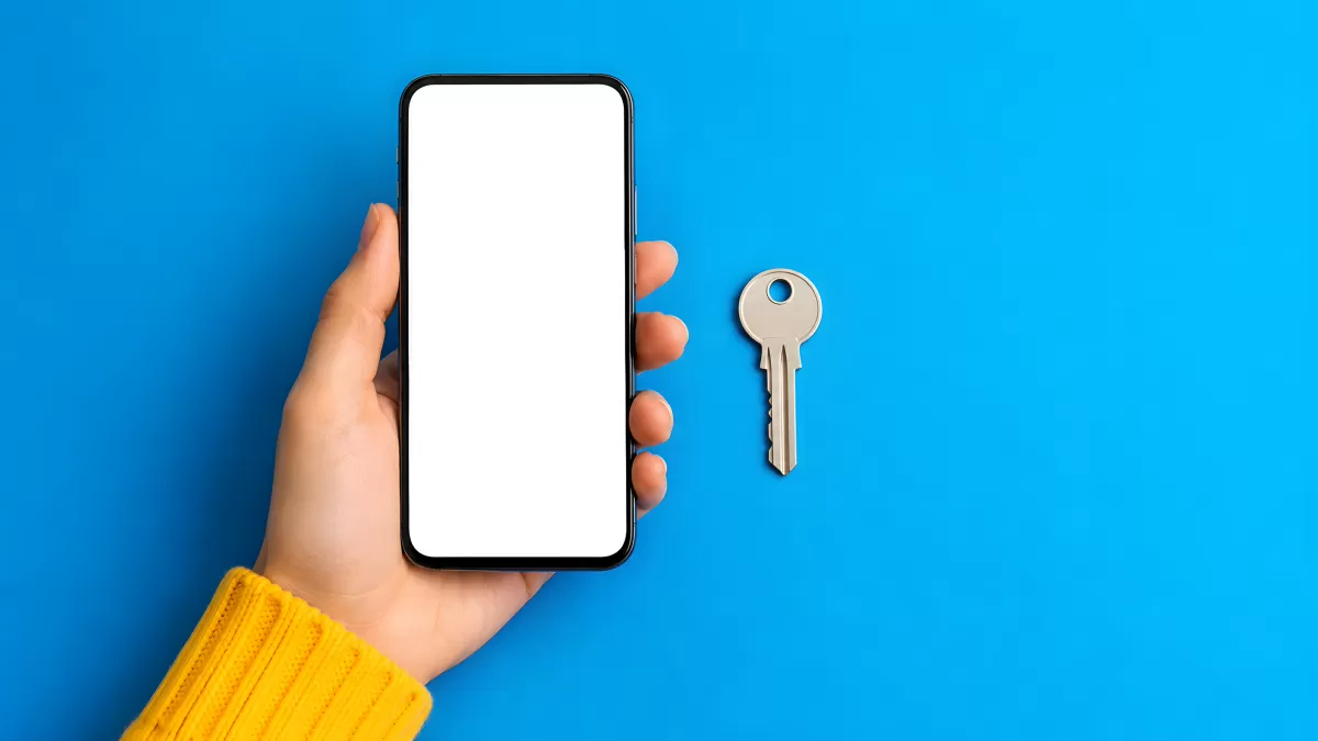 Hand hält Smartphone neben Schlüssel auf blauem Hintergrund
