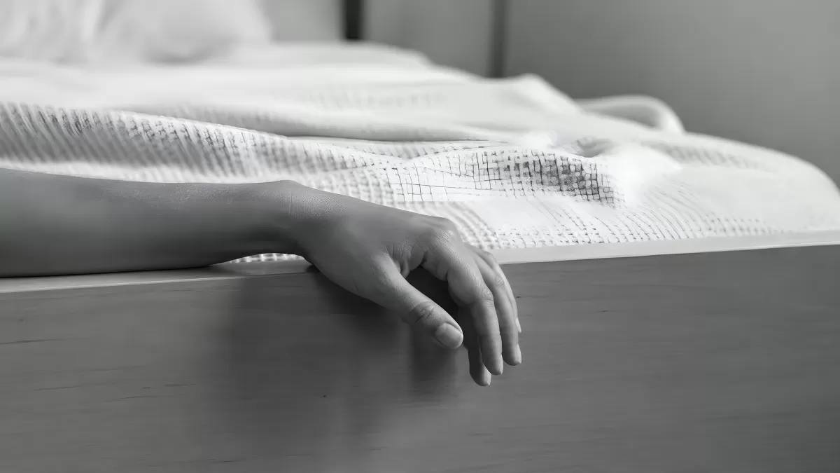 Hand hängt schlafend über den Bettrand in Schwarzweiß