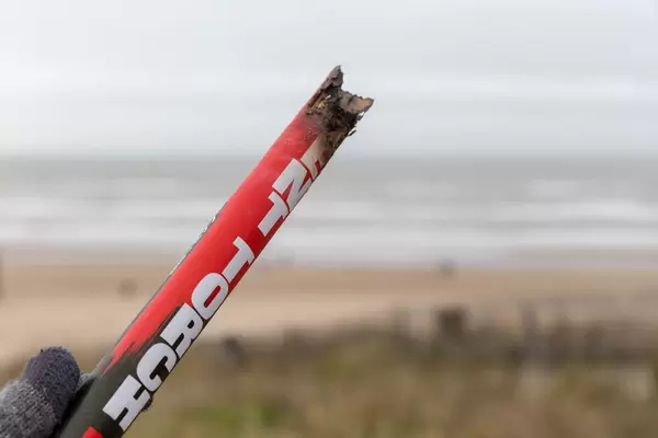 Hand hält abgebrannte Überreste von Silvester-Feuerwerk vor Strand